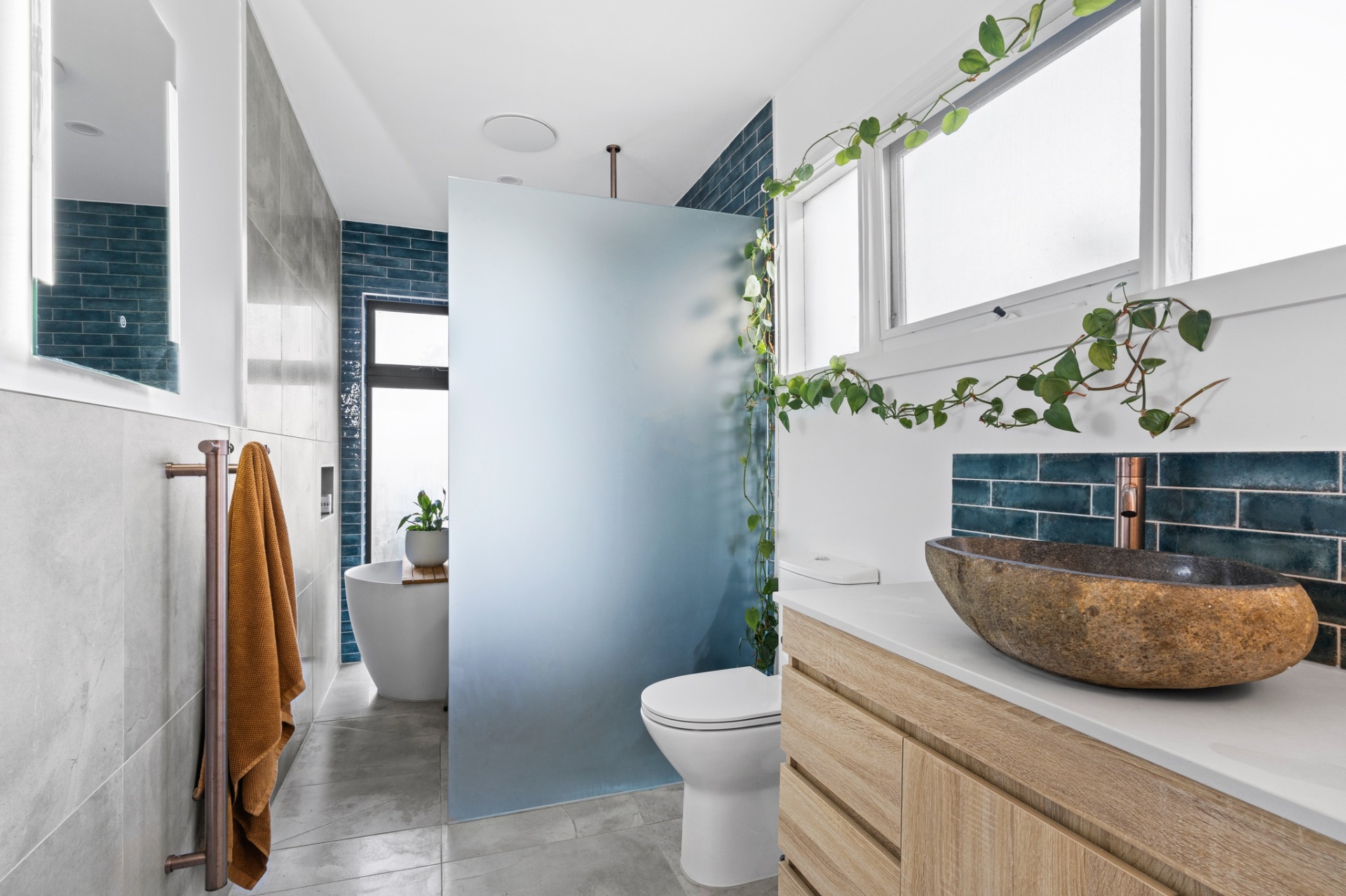 Frosted privacy screen, teal subway tile and raw stone vessel basin