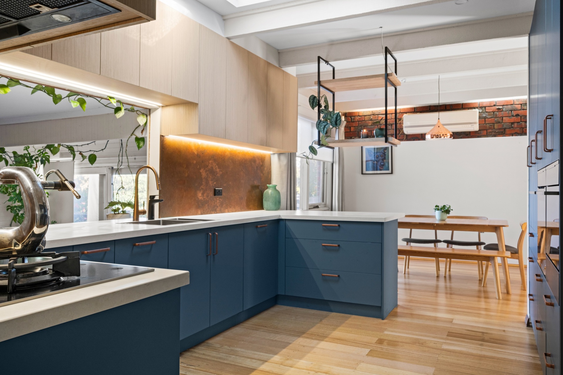 Warm kitchen with blue cabinetry and brass backsplash